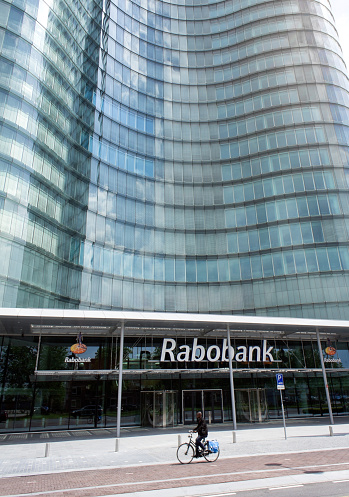 Utrecht, The Netherlands - May 19, 2012: The main entrance of the headquarters of the Rabobank International Holding BV along the Croeselaan in the city Utrecht, the Netherlands. The Rabobank is a dutch bank with offices around the world. The cyclist in front of the office building is an accidental passer-by.