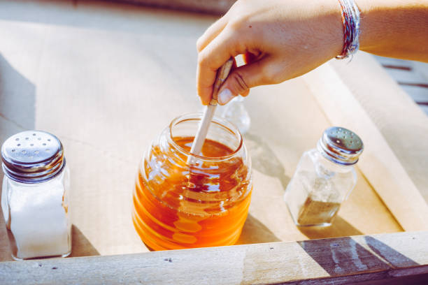 istock Girl's hand catching honey from a glass jar 1711074809