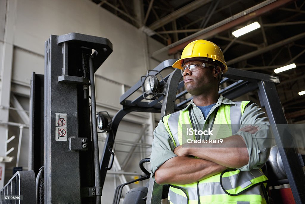 African American Pracownik stały obok forklift - Zbiór zdjęć royalty-free (Praca w fabryce)