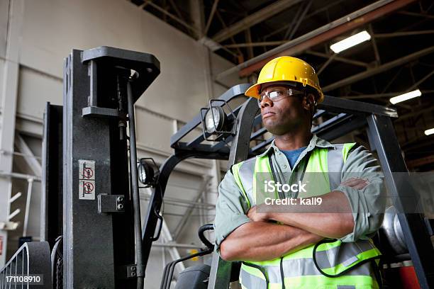 African American Pracownik Stały Obok Forklift - zdjęcia stockowe i więcej obrazów Praca w fabryce - Praca w fabryce, Afroamerykanin, Kask budowlany