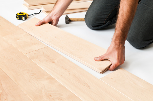 Close-up of man putting hardwood floor panels, floorboards.