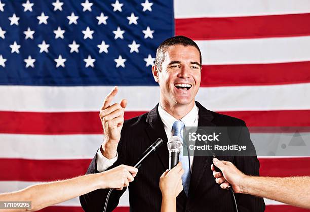 Przystojny Dojrzały Człowiek Mówiąc Do Mikrofonu Przed Flaga Stanów Zjednoczonych - zdjęcia stockowe i więcej obrazów Polityk