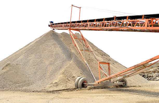 Rock Quarry Gravel pit with conveyor belt and mound of crushed gravel with sky in the background gravel mound stock pictures, royalty-free photos & images