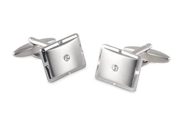 silver cufflinks with crystal inset a pair of elegant men's cufflinks made from bright metal with brushed faces and a small white crystal inset. Taken against a white background. cufflink stock pictures, royalty-free photos & images