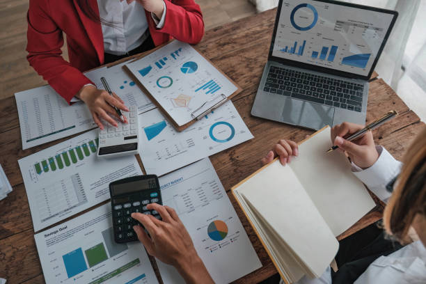 istock Business People Meeting using laptop computer,calculator,notebook,stock market chart paper for analysis Plans to improve quality next month. Conference Discussion Corporate Concept. 1711105907