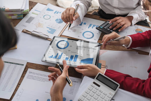 istock Business People Meeting using laptop computer,calculator,notebook,stock market chart paper for analysis Plans to improve quality next month. Conference Discussion Corporate Concept. 1711106427