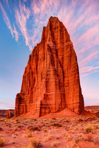 Sunrise illuminates the whispy pink clouds behind the Temple of the Sun and the Temple of the Moon.  Located at Capital Reef National Park in Utah.