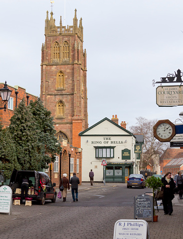 Taunton, UK - February 14, 2012: St James Street and St James Church, Taunton, Somerset. In the centre of the City near the Country Cricket ground is this street of independent shopw leading to The Ring of Bells pub and St James' Church tower. The photo was captured in early Spring and people are out shopping in their coast. Taunton is the County Town of Somerset and the hub of the local rural economy.