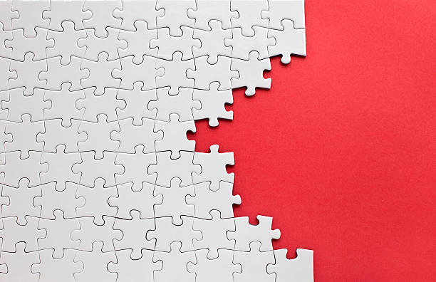 White jigsaw puzzle on a red background Jigsaw puzzle with copy space. jigsaw puzzle photos stock pictures, royalty-free photos & images