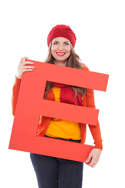 Woman holding letter E. Attractive woman in autumn clothes holding big 3D letter E and smiling at camera. Isolated on white. People with letters and numbers concept. Look for other images from this series. Click on image below for lightbox. 3d red letter e stock pictures, royalty-free photos & images