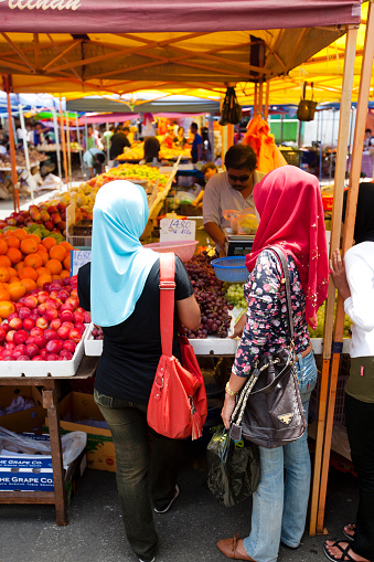 Kuching, Malaysia - March 3rd, 2012 : Two young women wearing traditional head scarfs buying fruit at the Kuching sunday market.