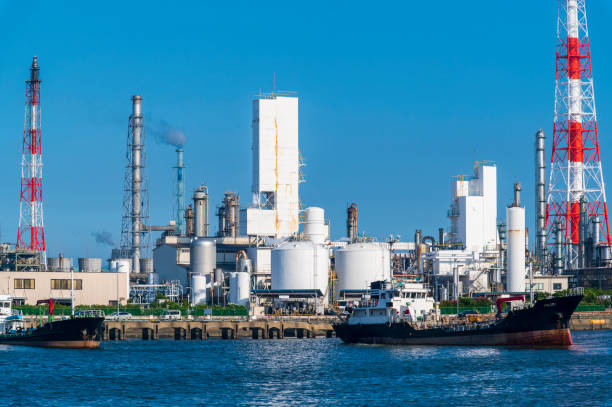 青い空の背景にガス貯蔵と煙突プラントからの煙を含むパイプラインの構造を持つ工業用石油化学精製所は、産業化学工場ゾーンを形成します。
