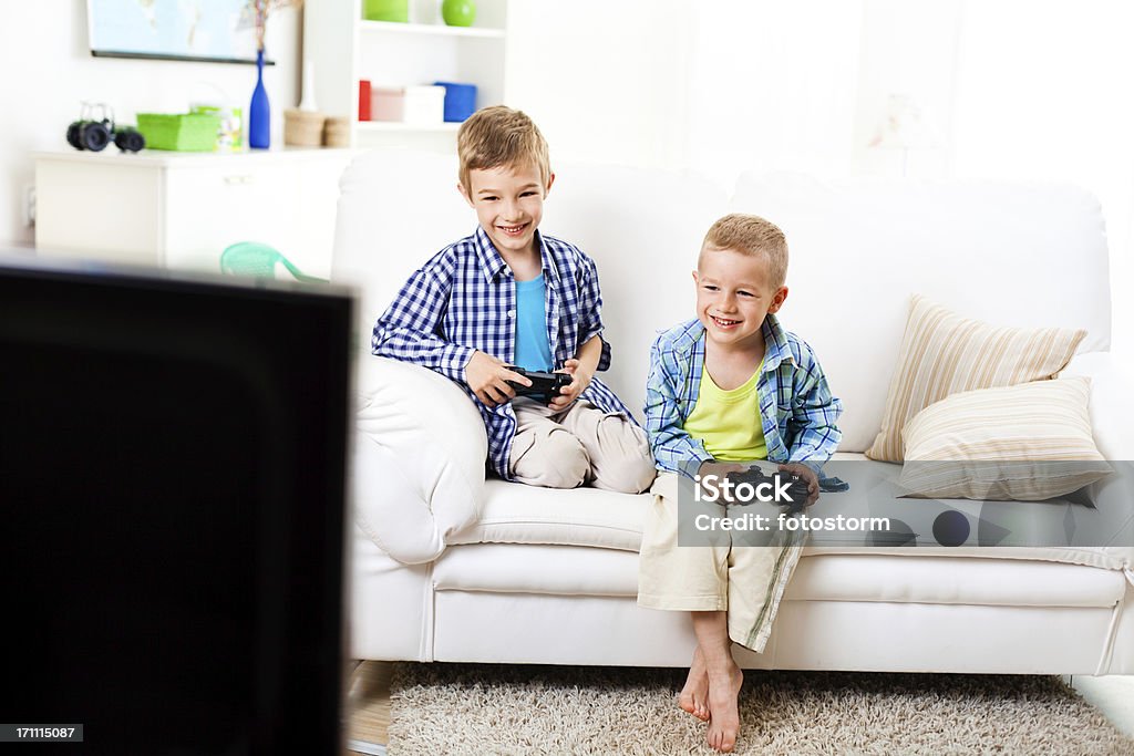 Children having fun, playing video games Children having fun at home, playing video games, holding game controllers. Boys Stock Photo