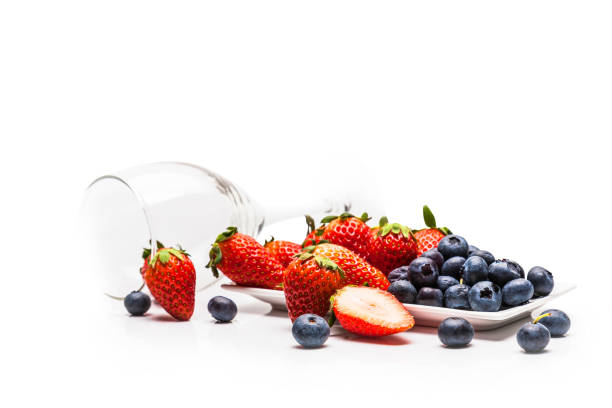 Red strawberries and fresh blueberries in bowls isolated on white background.