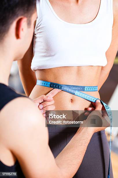 Instructor De Acondicionamiento Físico De Medición Waistline De Mujer En El Gimnasio Foto de stock y más banco de imágenes de Abdomen