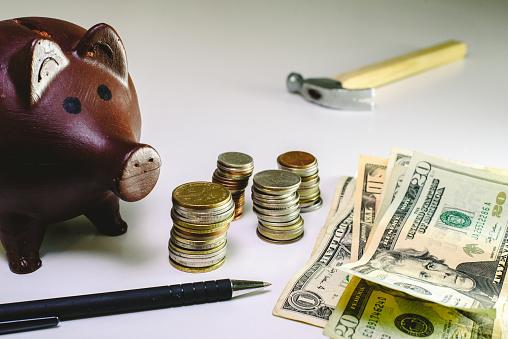 Money in coins and bills next to a piggy bank to save