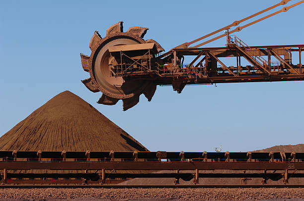 Iron Ore reclaimer machine and stockpile  A reclaimer used to move stockpiles of crushed iron ore on a mine site. the pilbara stock pictures, royalty-free photos & images