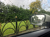 Car window and side mirror on a rainy day with nature background. Driving on rainy day