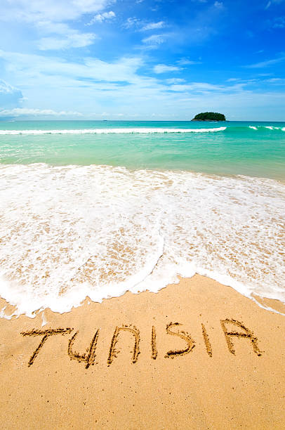 Tunisia Written on the Sand Tunisia written on the sand of a beautiful tropical beach. Visible are one island in the sea, turquoise water, little splashy waves, golden sand and beautiful cloudscape over the sea.See more images like this in: sousse tunisia stock pictures, royalty-free photos & images