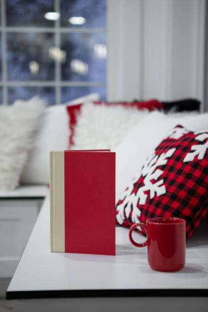 Holiday night reading Christmas living room bench with novel and coffee mug with winter in background red cushion covers stock pictures, royalty-free photos & images
