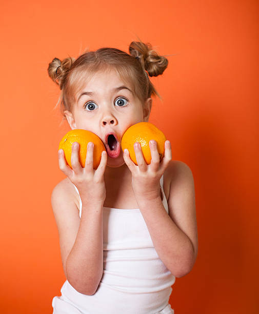 Cute Little Girl with Oranges on Orange Background stock photo