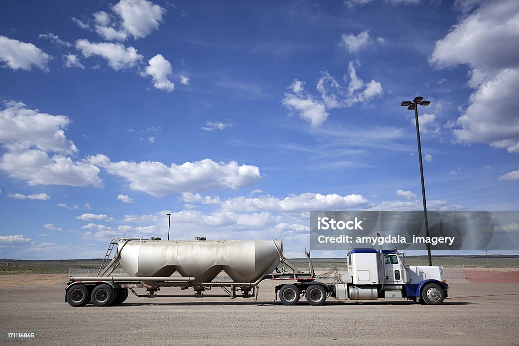 fuel truck tanker petroleum truck semi in parking lot underneath a cloud filled blue sky conjures notions of environmental contrasts.  horizontal composition with wide angle lens and copy space in sky take on the jicarilla apache reservation of northern new mexico. Semi-Truck Stock Photo