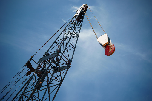 The boom and hook of a construction crane phorographed with sky background.