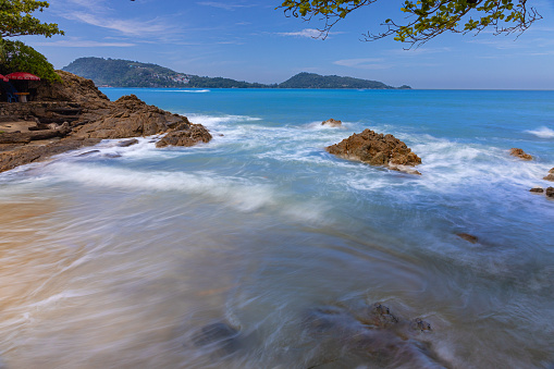 Long exposure of waves crushing against rocks on Patong Beach in Phuket Thailand