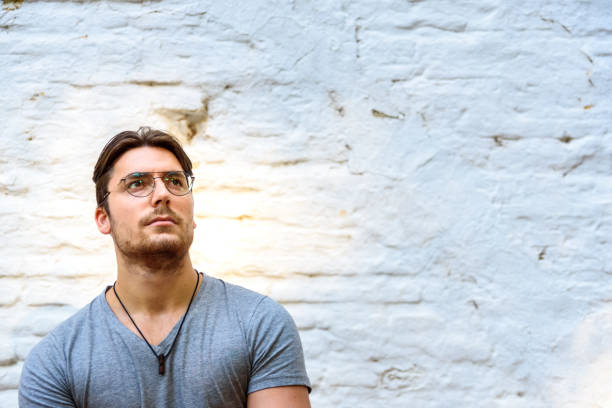 istock Young male model with glasses posing isolated on a white brick wall. 1711230501