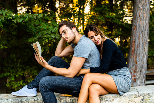Couple in love hugging, read a book in a natural garden.