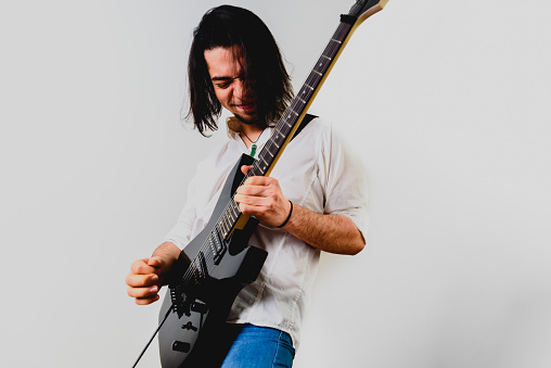 Guitarist posing with his electric guitar, white background.