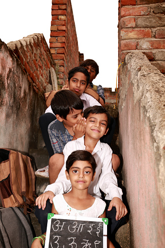 Cheerful elementary age school students sitting in a row at home wearing school uniform in staircase.