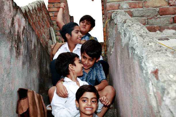 Smiling Indian family sitting together on a rock, wearing casual clothes and looking joyfully at the camera. Enjoying time outdoors, radiating happiness and love