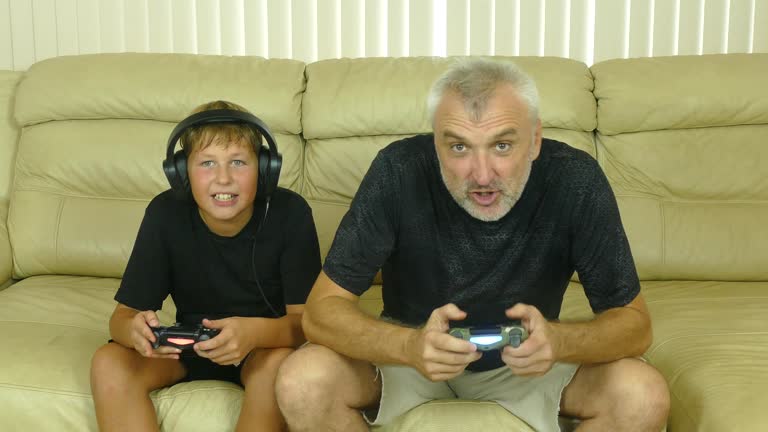 gray-haired man and a boy play computer games with passion