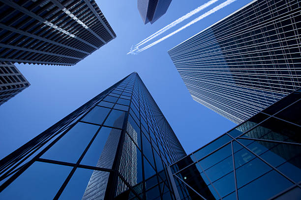 Skyscrapers with Jumbo Jet Tall modern skyscrapers with a jumbo jet passing over leaving a sharp contrail. wow airlines stock pictures, royalty-free photos & images