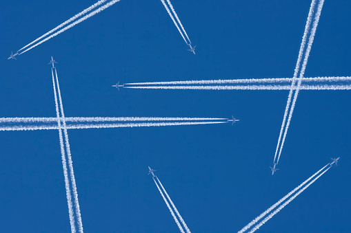 Vapor trails from airplanes in mid-air against a blue sky