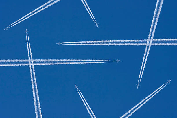 Vapor trails from airplanes in mid-air against a blue sky Airplanes in a Blue Sky with Vapor Trail, Air Traffic vapor trail photos stock pictures, royalty-free photos & images