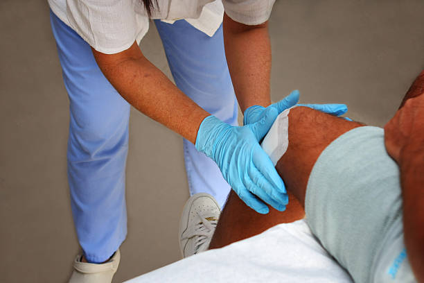enfermeira é a prestação de cuidados aos feridos, mudando o joelho no peito - gauze bandage adhesive bandage healthcare and medicine - fotografias e filmes do acervo
