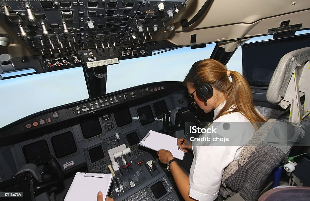 Commercial jet flyin...beautiful woman pilot checking data In cockpit of an airplane Adult Stock Photo