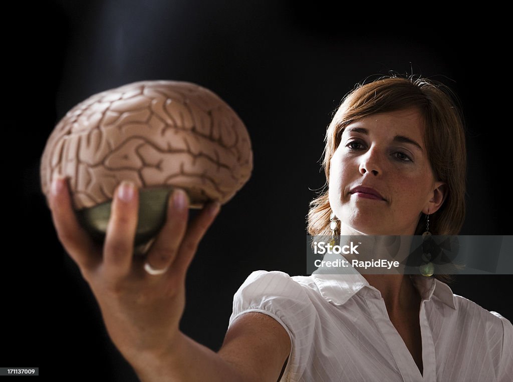 Brainy woman Young woman holds an accurate medical model of a human brain. Camera: Canon EOS 1Ds Mark III. One Woman Only Stock Photo