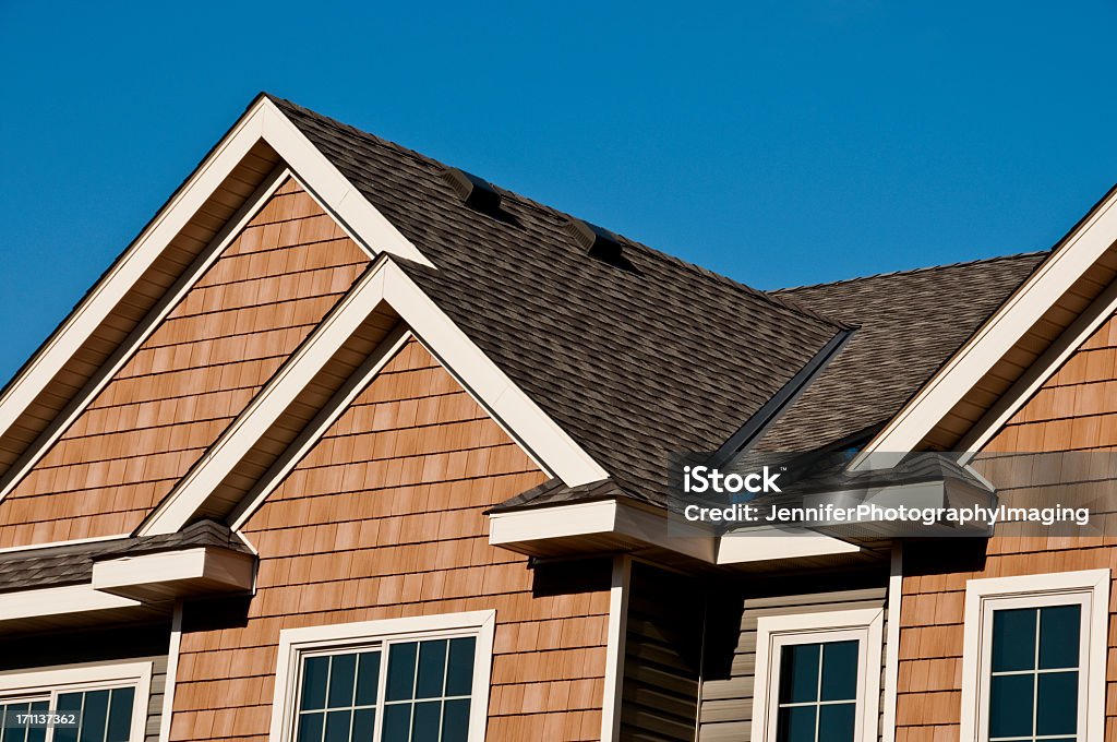 Modern architectural roofing detail Detail of a newly constructed building, showing the roof line, siding, shingles and windows. Rooftop Stock Photo