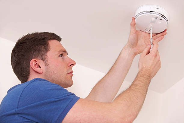Man Installing Smoke Or Carbon Monoxide Detector Simple safety precaution smoke detector photos stock pictures, royalty-free photos & images