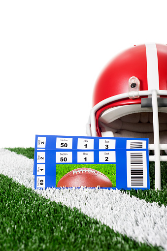 Football Helmet- TicketsOn artificial turf sits a red football helmet behind two football tickets. The tickets are for section 50, row 1, and seats 2 and 3. It looks to be a great advertisement as football season draws near. 