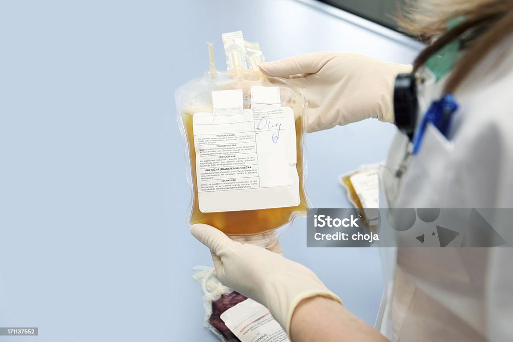 Doctor in a blood bank holding  bag  with white cells Doctor in a blood bank is holding blood bag  with red blood cells Blood Plasma Stock Photo
