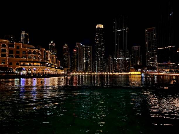 The Night Cruise A boat sails through the water, the city of Dubai glistening all around it in the night. dubai mall stock pictures, royalty-free photos & images
