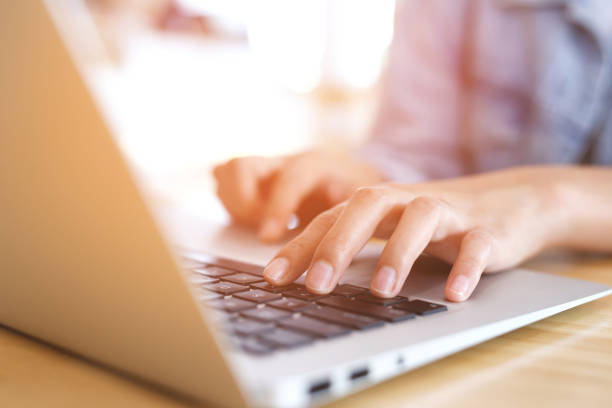 istock lifestyle man close up hand keyboard sit work on wooden table using a laptop computer to work from home and search information social network online. filter tone vintage style.  wfh. Social Distancing 1711376091