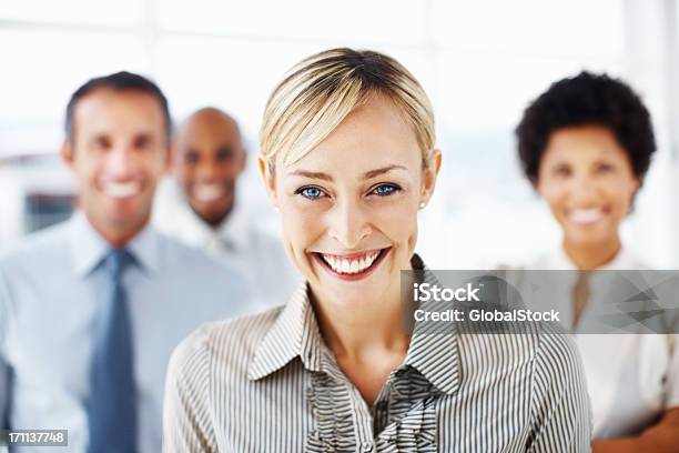 Donna Daffari Sorridente Con I Colleghi In Background - Fotografie stock e altre immagini di Abbigliamento formale