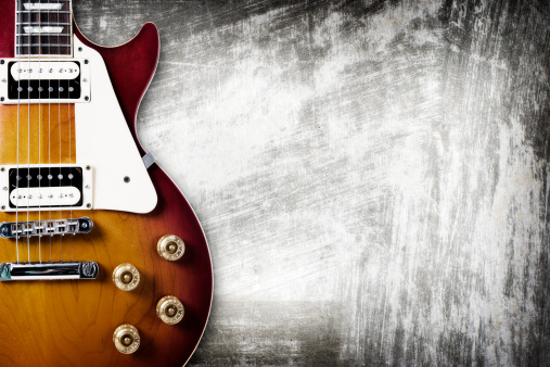 Red electric guitar on a wooden background. Empty space, close-up.