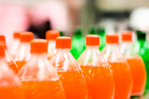 Bottles of orange soda in a supermarket, shot with very shallow depth of field. Camera: Canon EOS 1Ds Mark III.