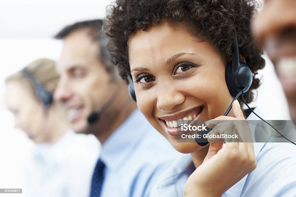 telephonnist feminino sorrindo entre seus colegas de trabalho - Foto de stock de 20-24 Anos royalty-free